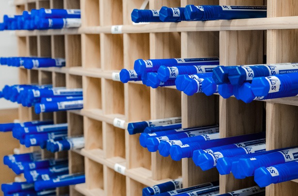 Regal mit Qualas Laserschweißdrähten als gerichtete Stäbe in blauen Röhrchen.