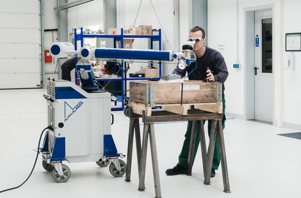 Mitarbeiter schweißßt großes Bauteil mit mobilen Laserschweißgerät in Halle.