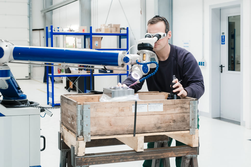 Wir schweissen direkt bei Ihnen vor Ort. Sie sparen Zeit und haben wenig Aufwand. Mobiles Laserschweißgerät wird am Werkstück ausgerichtet, Schweißer trägt eine Schutzbrille und schaut durch das Okular.